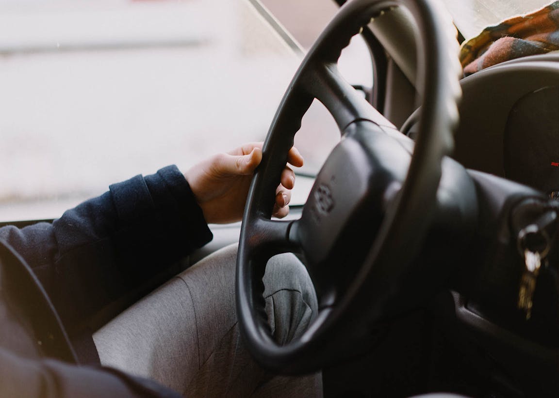 A hand gently holds the steering wheel of a vehicle.
